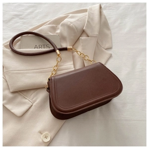Detailed view of dark brown leather saddle bag with gold chunky chain and matte finish