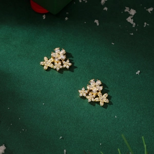 Detailed macro shot of gold flower studs with sparkling zircon on a dark green felt background