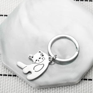 Detail of a silver cat-shaped stainless steel keychain with hollow-out design on marble