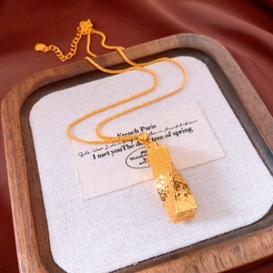 Close-up of a 24k gold plated twisted pillar pendant necklace with floral texture