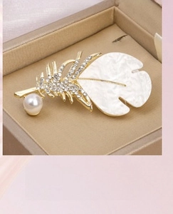 Macro shot of an elegant feather brooch with zircons and pearls in a jewelry box