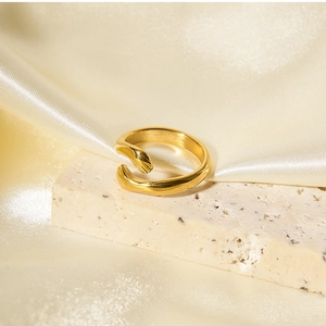 Close-up of gold hugging hands open ring on beige stone and champagne silk fabric