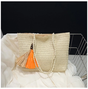 Detail of beige straw tote bag with colorful tassels and wooden beads in a wire basket
