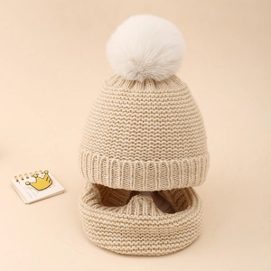 Detail of beige knit baby hat and scarf set with honeycomb texture and white pom-pom