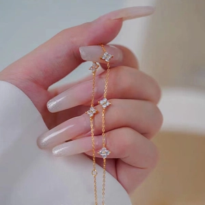 Elegant gold four-leaf clover flower bracelet with white crystals and fringe tassels