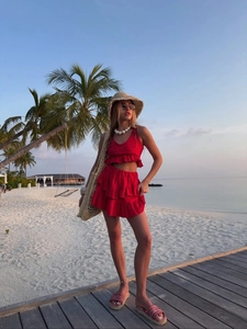 Detail of red tiered ruffle skirt and sleeveless top set on a sunset beach background