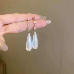 Close-up of elegant silver drop earrings with crystals and large white teardrop pearls