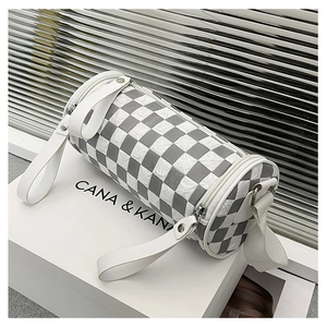 Detail of checkered cylinder crossbody bag with wide shoulder strap and metal hardware