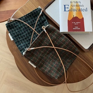 Detail view of retro plaid tweed crossbody bags with leather straps on a wooden table