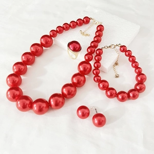 Detail of red faux pearl jewelry set featuring necklace and earrings on white background