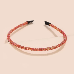 Detail of thin orange-red glitter headband with shimmering sequins and black ends