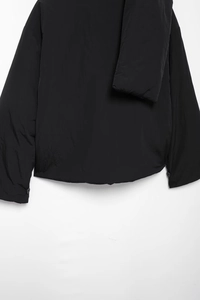 Detailansicht der Rückseite der schwarzen Pufferjacke mit Saum und geknöpften Bündchen