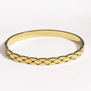 Détail d'un bracelet doré avec gravure croisée et accents de diamants étincelants