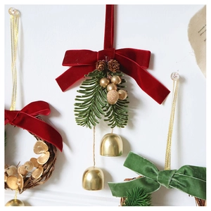 Close-up of velvet bows, golden bells, and pine cones on a Christmas wreath hanging