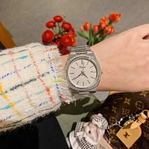 Detail showing Dimini watch with white dial, calendar window and silver steel strap