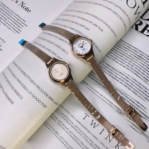 Close-up of two rose gold quartz watches with mesh bands on a vintage newspaper background