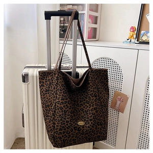 Detail of large leopard print tote bag hanging on a suitcase handle in a home setting