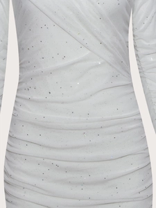 Close-up of white sequin fabric with elegant ruched details on a slim evening dress