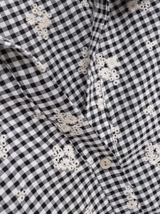 Détail d'une chemise à carreaux avec broderie florale et bouton nacré élégant