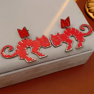Detail of red enamel cat earrings with silver needles on a gray jewelry box