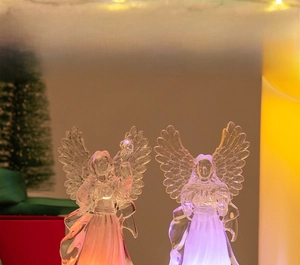 Close-up of LED glowing acrylic angel ornaments with warm orange and purple light