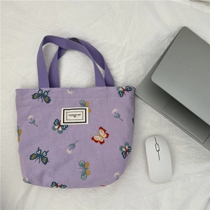 Détail du sac en toile violette avec broderies papillons et étiquette tissée