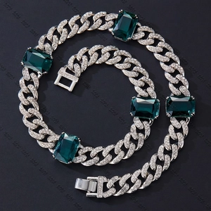 Dettaglio di collana e bracciale a maglia cubana con pietre color smeraldo e strass