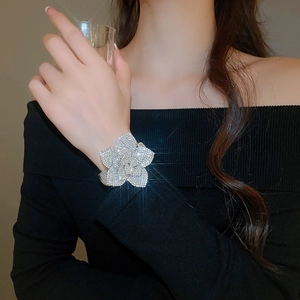 Macro view of adjustable silver flower bangle with sparkling rhinestones worn by a model