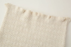 Gros plan détaillé du tissu en maille crème montrant textures et bords festonnés