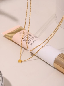Detail of gold double-layer necklace with star pendant and pearl on soft beige background