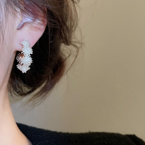 Close-up of elegant silver flower stud earring on model showing fine zircon details