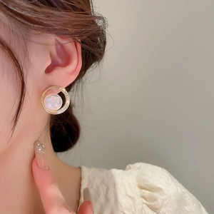 Close-up of gold-plated hoop earring with opal-like pearl and sparkling zircon accents