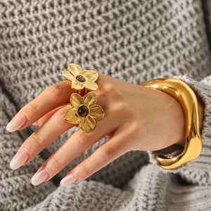 Polished gold wave bangle and double flower ring set shown on a grey knit sweater sleeve