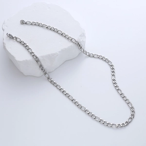 Macro view of silver Figaro chain necklace resting on white textured stone background