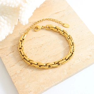 Minimalist gold titanium steel curb chain bracelet with K18 tag on marble surface