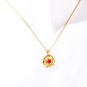 Gold stainless steel coin necklace featuring a round pendant with a red birthstone