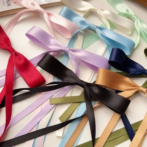 Close-up of assorted colorful satin ribbon bow clips with a glossy finish on white base
