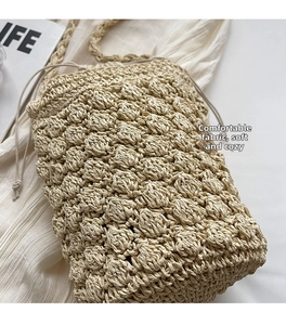 Close-up of popcorn texture weave on beige straw bucket bag with drawstring closure