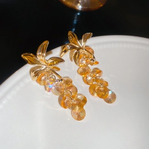 Gros plan de boucles d'oreilles en cristal champagne avec fleurs dorées sur plat blanc