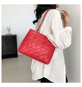 Detail showing red quilted tote bag with gold chain strap worn as a shoulder bag