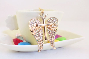 Detailed macro view of a gold angel wing cross keychain with sparkling colorful rhinestones
