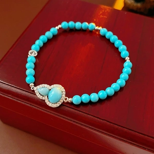 Close-up of turquoise gourd charm bracelet on a vintage wood box showing silver micro-pave