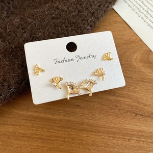 Vue détaillée de trois paires de boucles d'oreilles feuilles de ginkgo dorées et perles