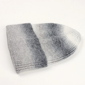 Close-up of grey and white gradient knit beanie showing fluffy mohair texture and pattern