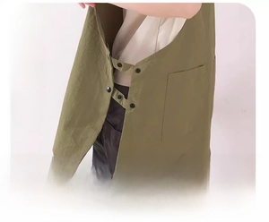 Detail view of adjustable side snaps and durable canvas fabric on a green work apron
