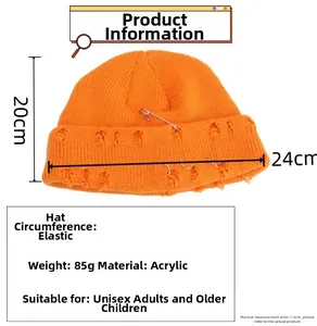 Detail view of orange knit beanie featuring metal rings and paperclip pin decorative accents