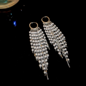 Detail of 18k gold plated long fringe earrings with elegant pearls on black background