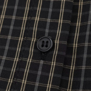 Macro view of black resin buttons and detailed plaid pattern on cotton blend shirt