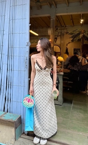 Detail of white polka dot slip dress featuring black lace trim and retro aesthetic style