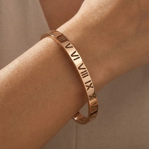 Détail du bracelet ajouré or rose avec chiffres romains et cristaux brillants au poignet